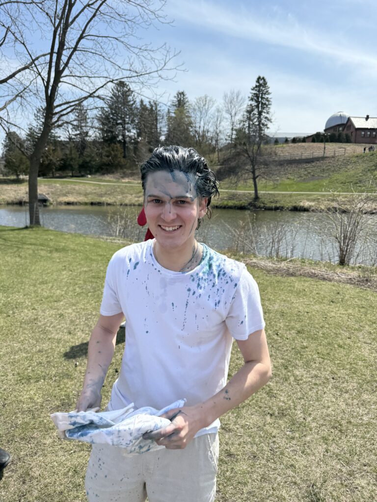 Smiling person with hair and forehead in blue with white shirt