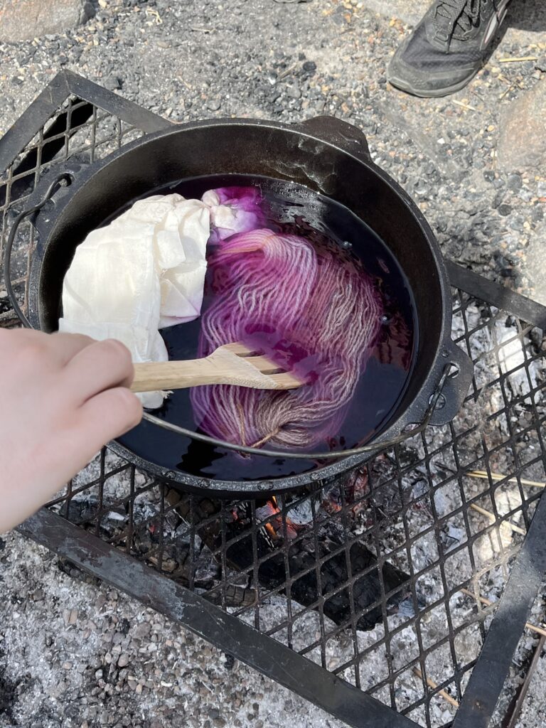 Spoon stirring purple dye in metal pot
